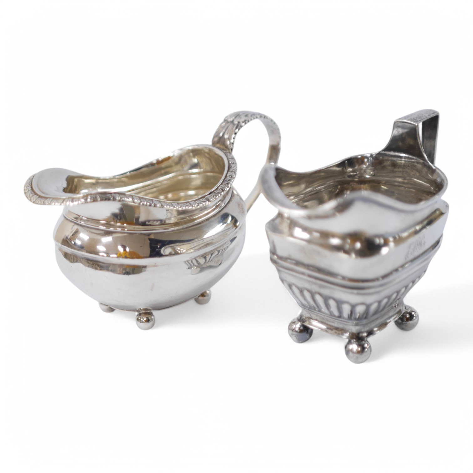 Two George III silver cream jugs, one demi-fluted, with engraved inscription to the base, London, 1807, both with engraved monogram, 11.3oz. Condition - poor to fair